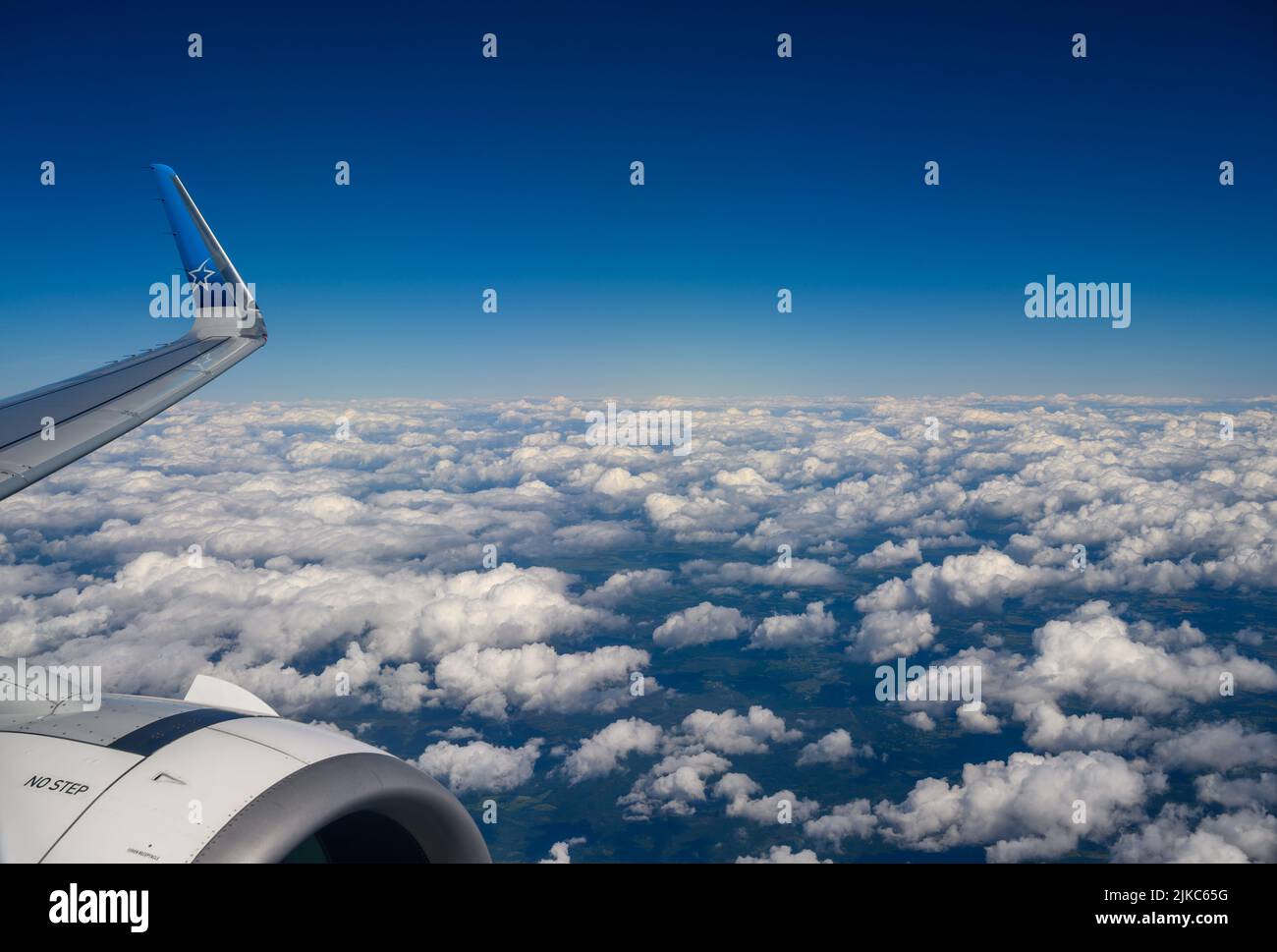 Above the clouds: The wing tip and jet engine of an Air Transat Airbus A321 flying over white cumulus clouds above south coast of England. Stock Photo