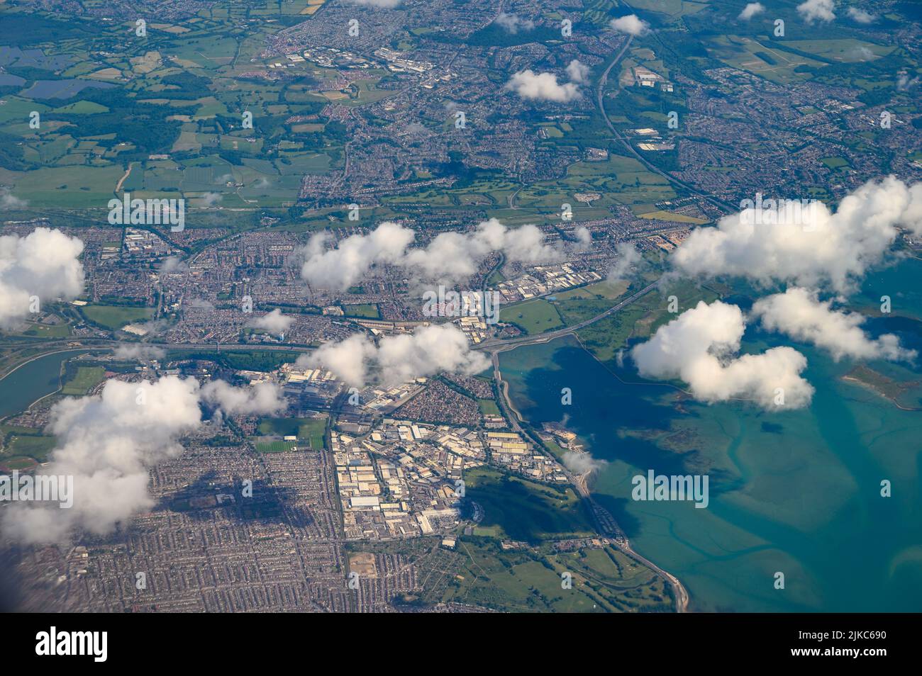 Aerial view over Portsmouth, Hampshire, in good weather with a few fluffy cumulus clouds photographed from a passenger jet. Stock Photo