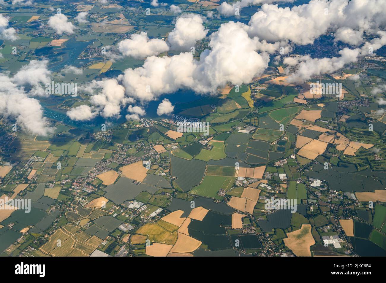 Aerial view over West Sussex countryside and Chichester Harbour, in good weather with a white cumulus clouds photographed from a passenger jet. Stock Photo