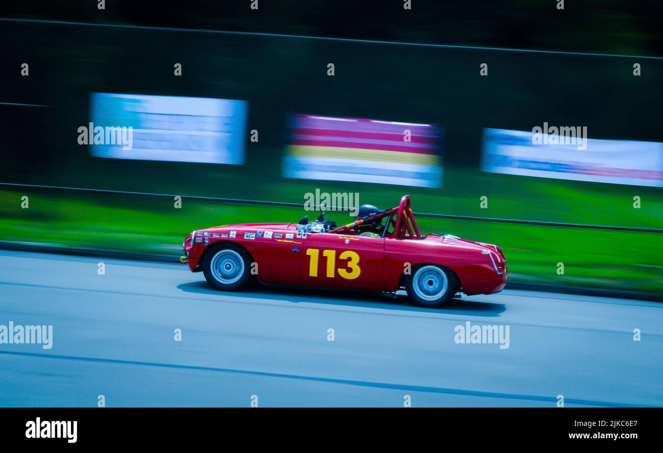 A classic red car driving fast on a racing track at the Pittsburgh