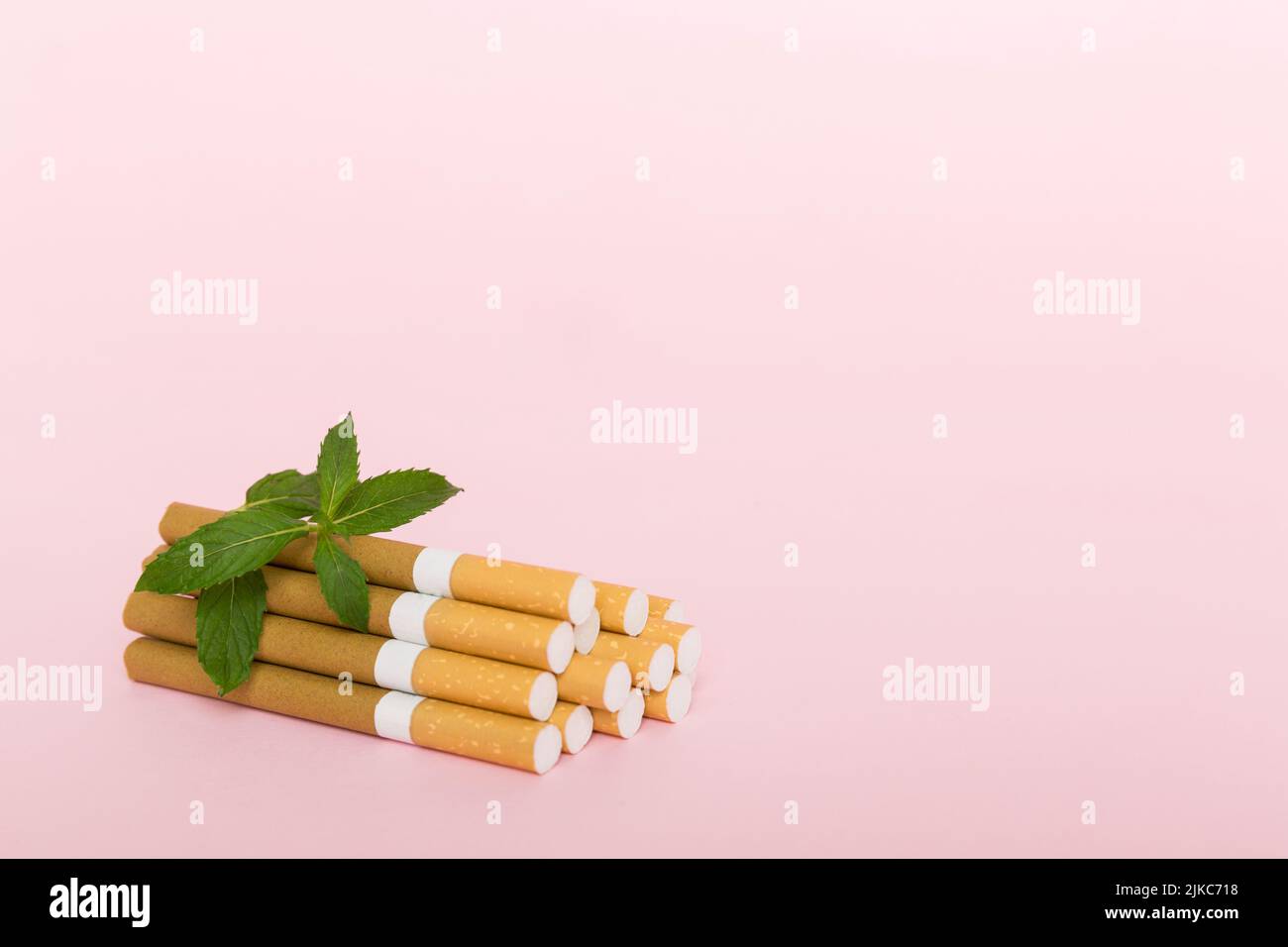 Menthol cigarettes and fresh mint leaves on colored background, Many