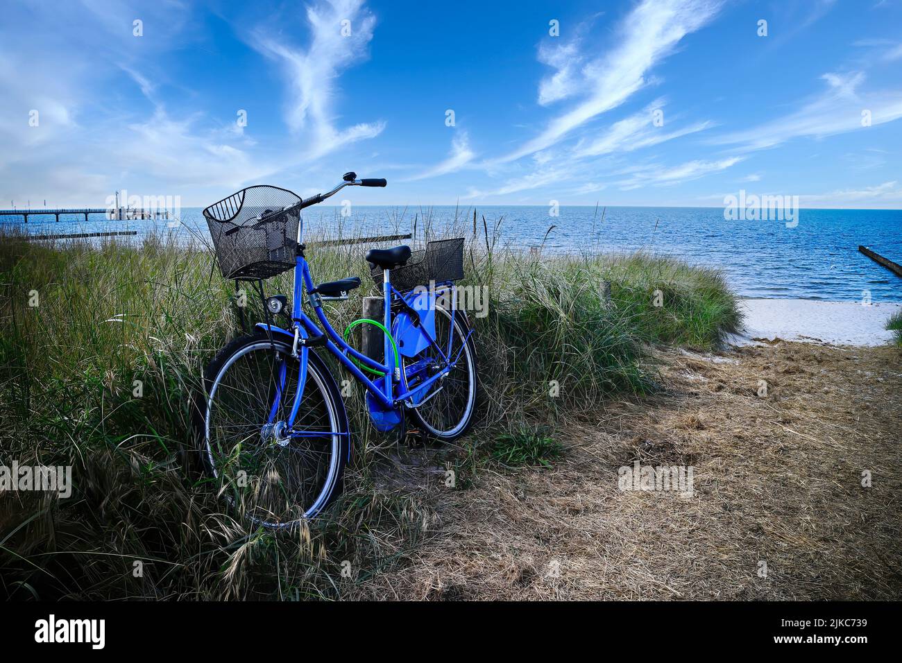 Blue bicycle on a sand dune with the beach and sea in the background Stock Photo