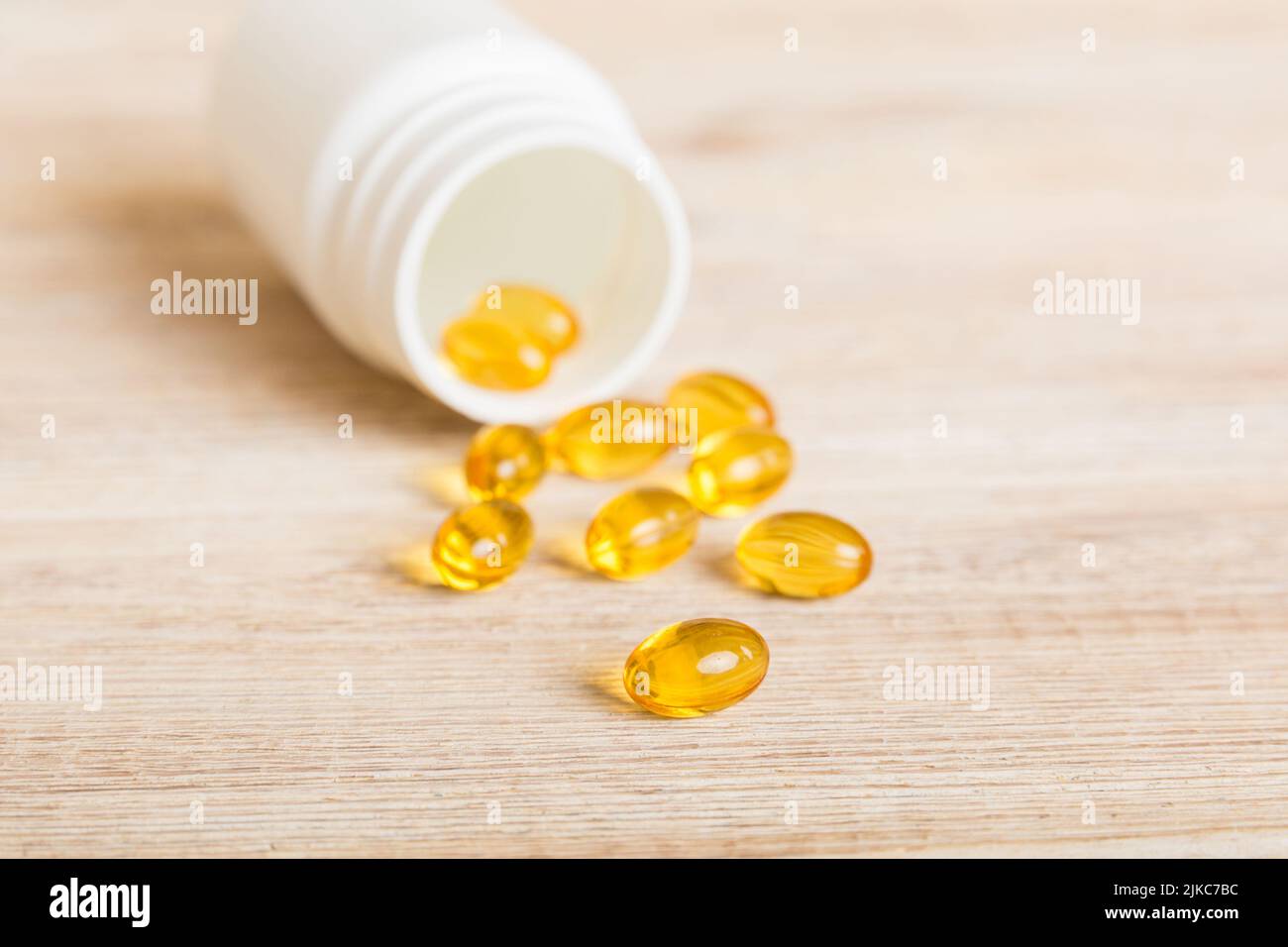 Soft gels pills with Omega3 oil spilling out of pill bottle closeup