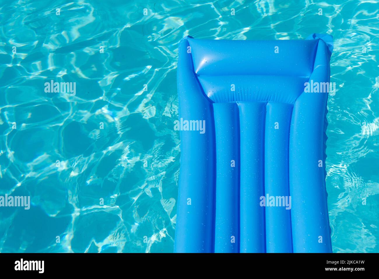 https://c8.alamy.com/comp/2JKCA1W/bright-blue-summer-pool-lounger-float-on-a-rippled-swimming-pool-2JKCA1W.jpg