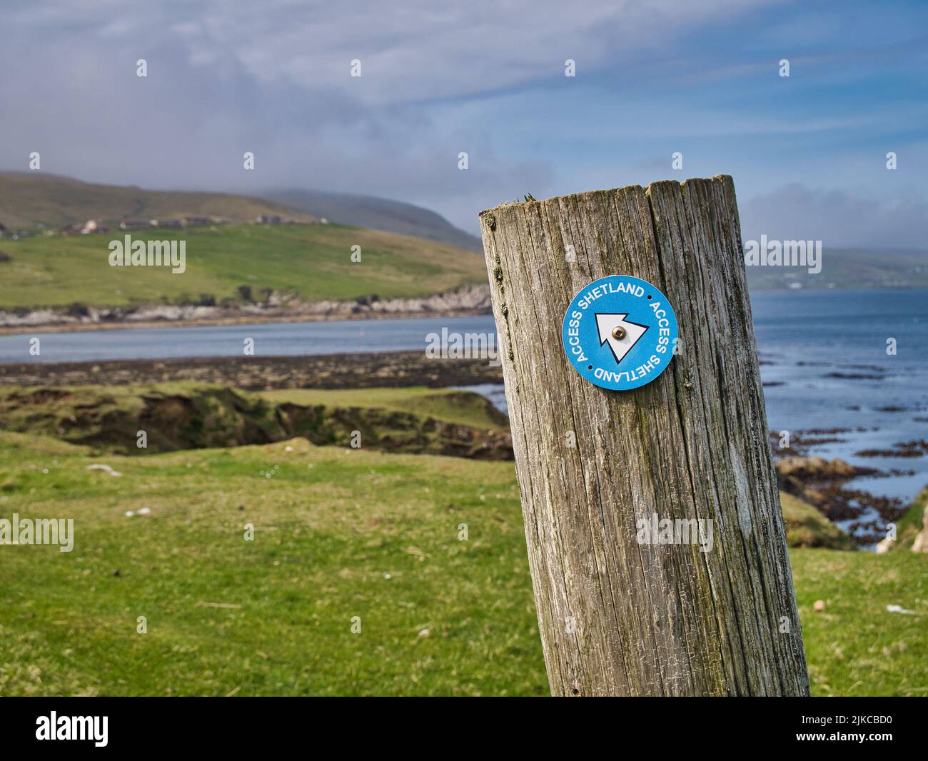 Fixed to a wooden post on the coast, a blue and white Access Shetland sign near Sandwick in Shetland, UK shows the way to walkers and hikers. Stock Photo