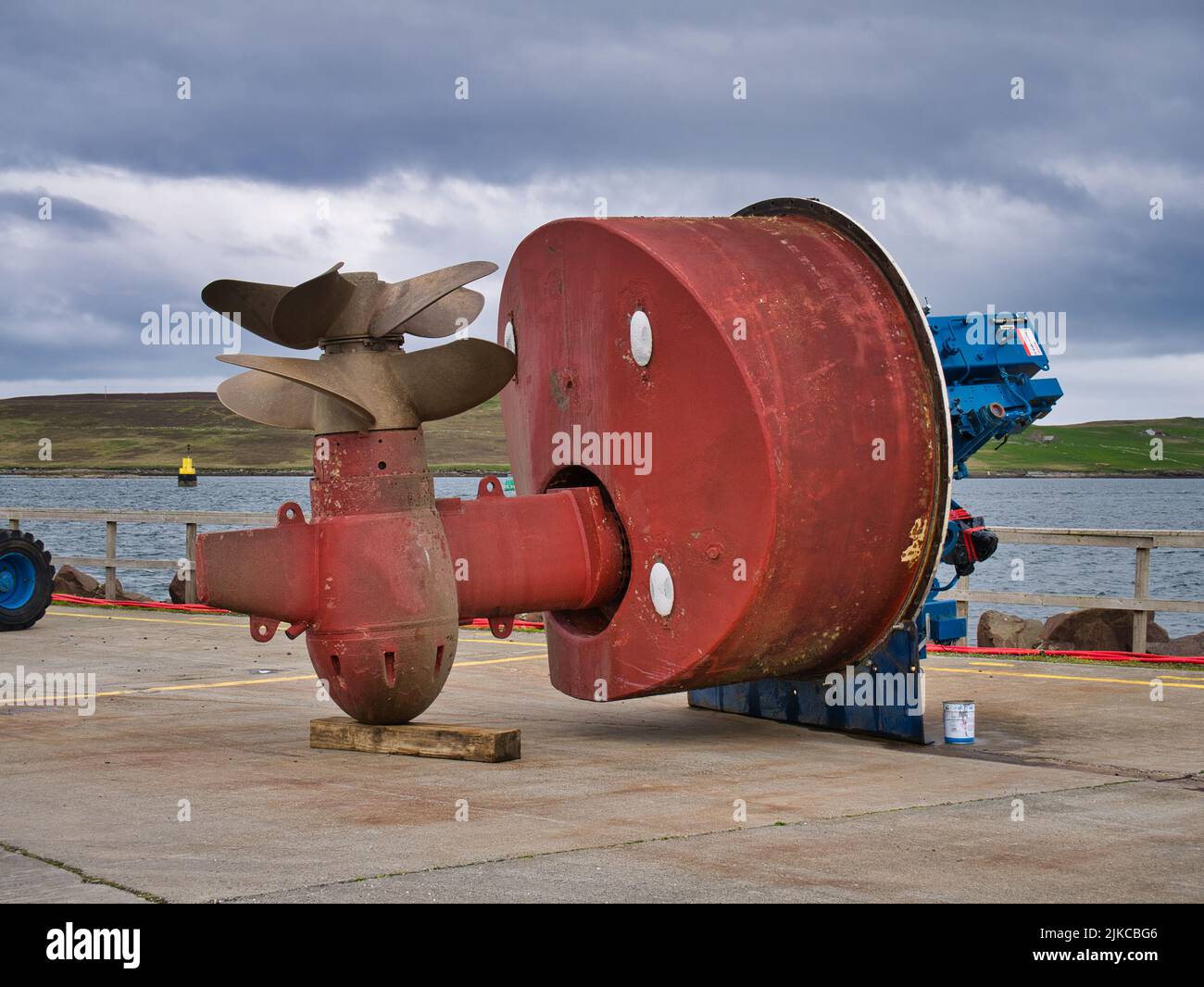 A large, red, twin propellor - twin screw screw azimuth thruster unit on the quay at Lerwick harbour in Shetland, UK. Taken on a cloudy, overcast day. Stock Photo