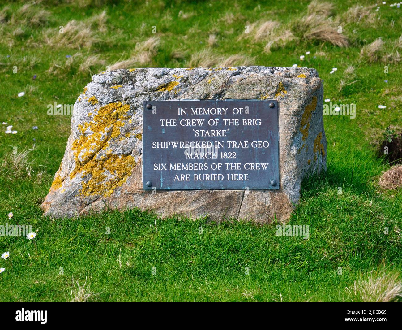 A rectangular plaque attached to a rock marks the graves of six of the crew who died when the brig Starke was shipwrecked near by in 1822. Stock Photo