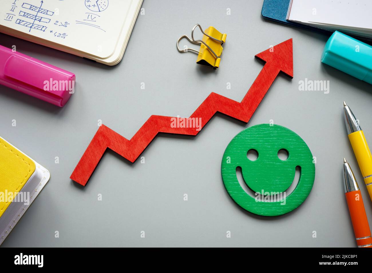 Customer satisfaction and feedback concept. Rising arrow and smiley on the desk. Stock Photo