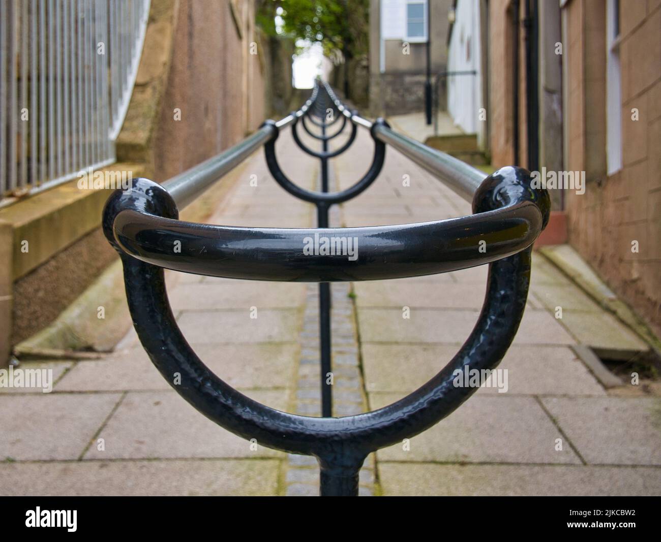 A double metal handrail up a steep pedestrian granite-flagged footpath between buildings in Lerwick, Shetland, UK. Stock Photo