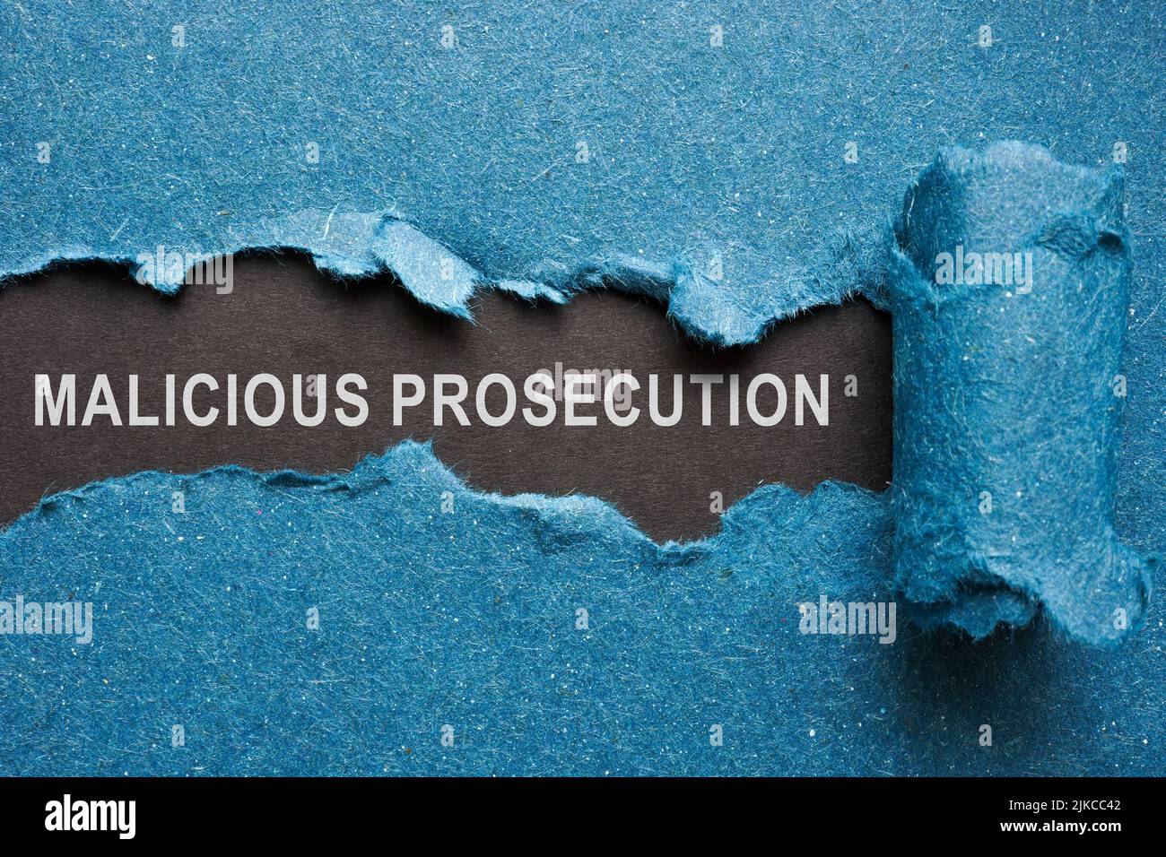 Words malicious prosecution on dark paper under blue one. Stock Photo