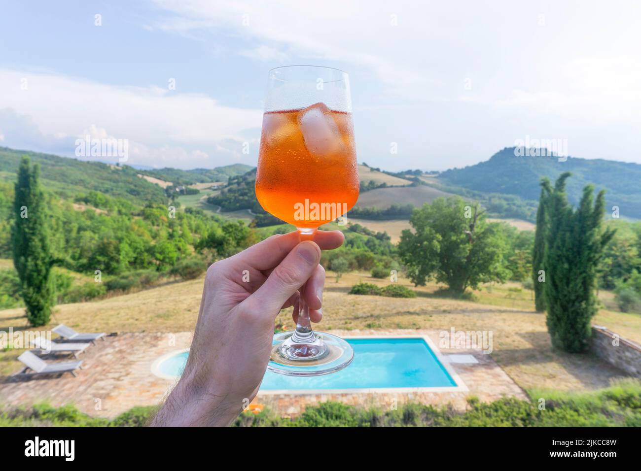 Hand holding an aperitif spritz cocktail with a beautiful italian view behind Stock Photo