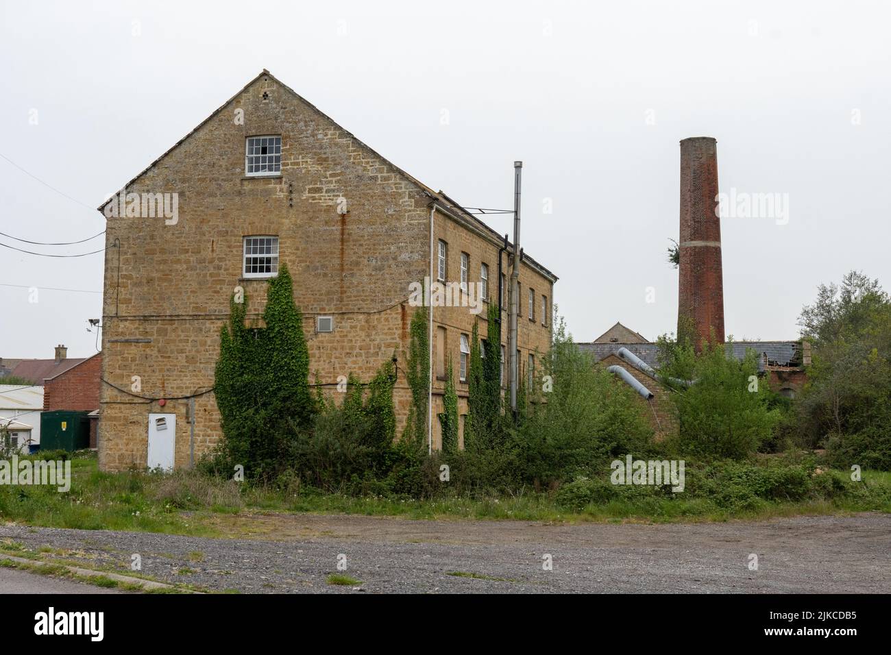 An old factory by a road on a cloudy sky background Stock Photo - Alamy