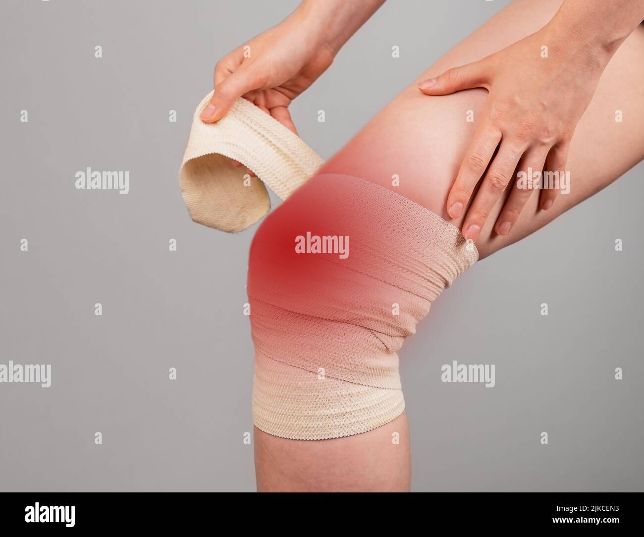 Woman wrapping elastic bandage around painful knee to relieve pain or prevent injury. Female suffering from leg discomfort. Sprained ligaments, torn cartilage. High quality photo Stock Photo