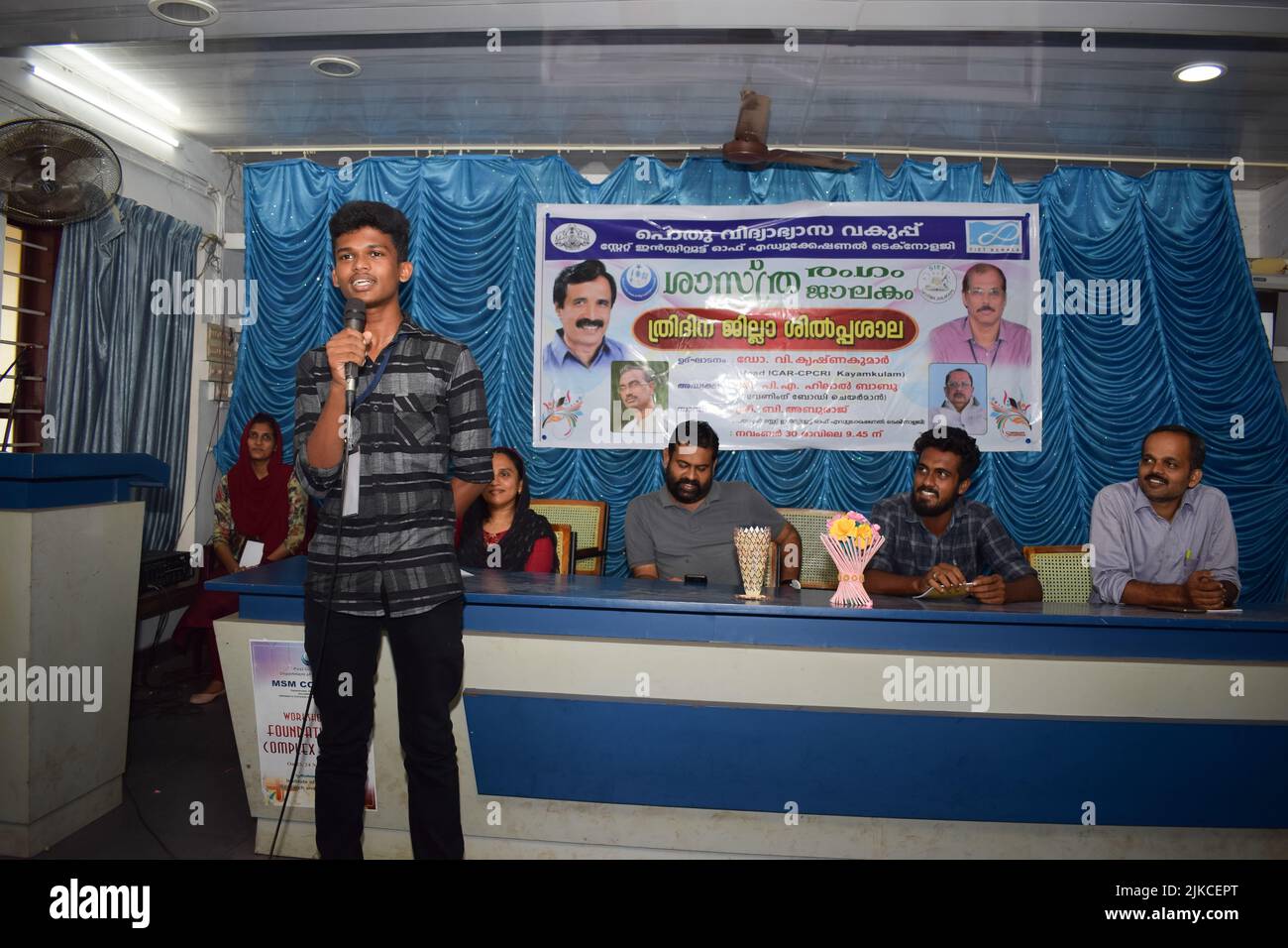 Indian boy talking in front of the class using a microphone or mike. Stock Photo