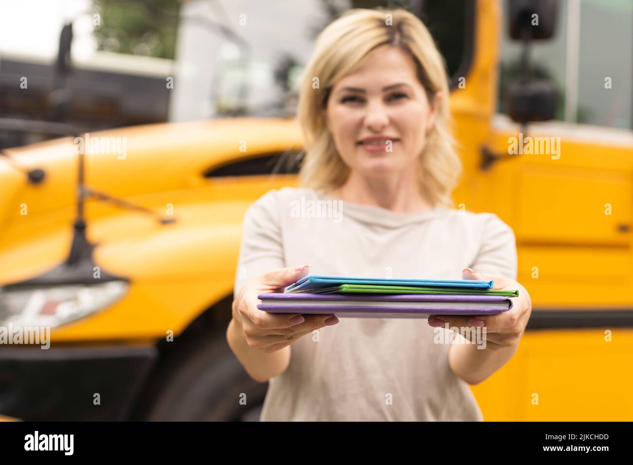 Portrait of cheerful teacher standing near the school bus Stock Photo ...