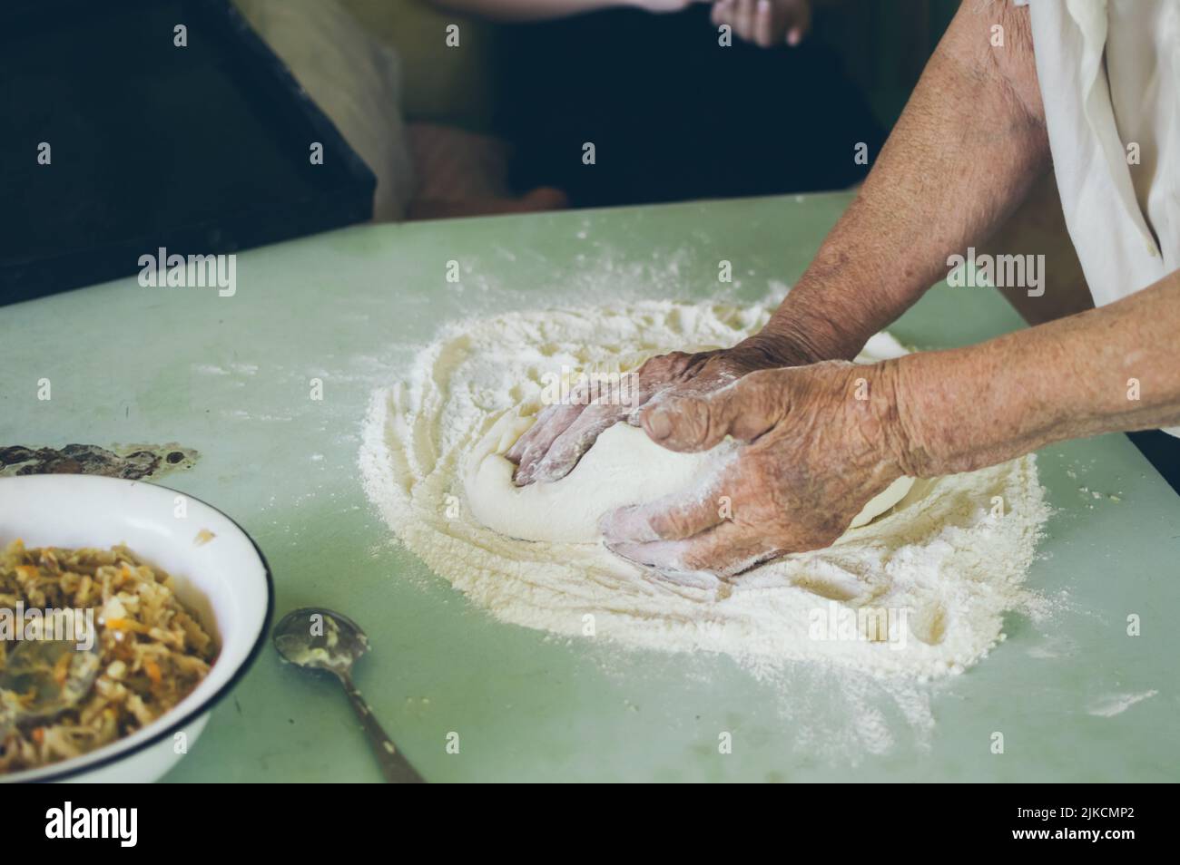 Old woman kneads dough for patties with flour Stock Photo - Alamy
