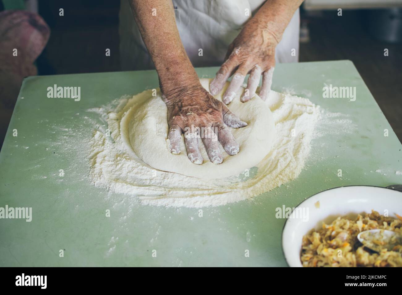 Old woman kneads dough for patties with flour Stock Photo - Alamy
