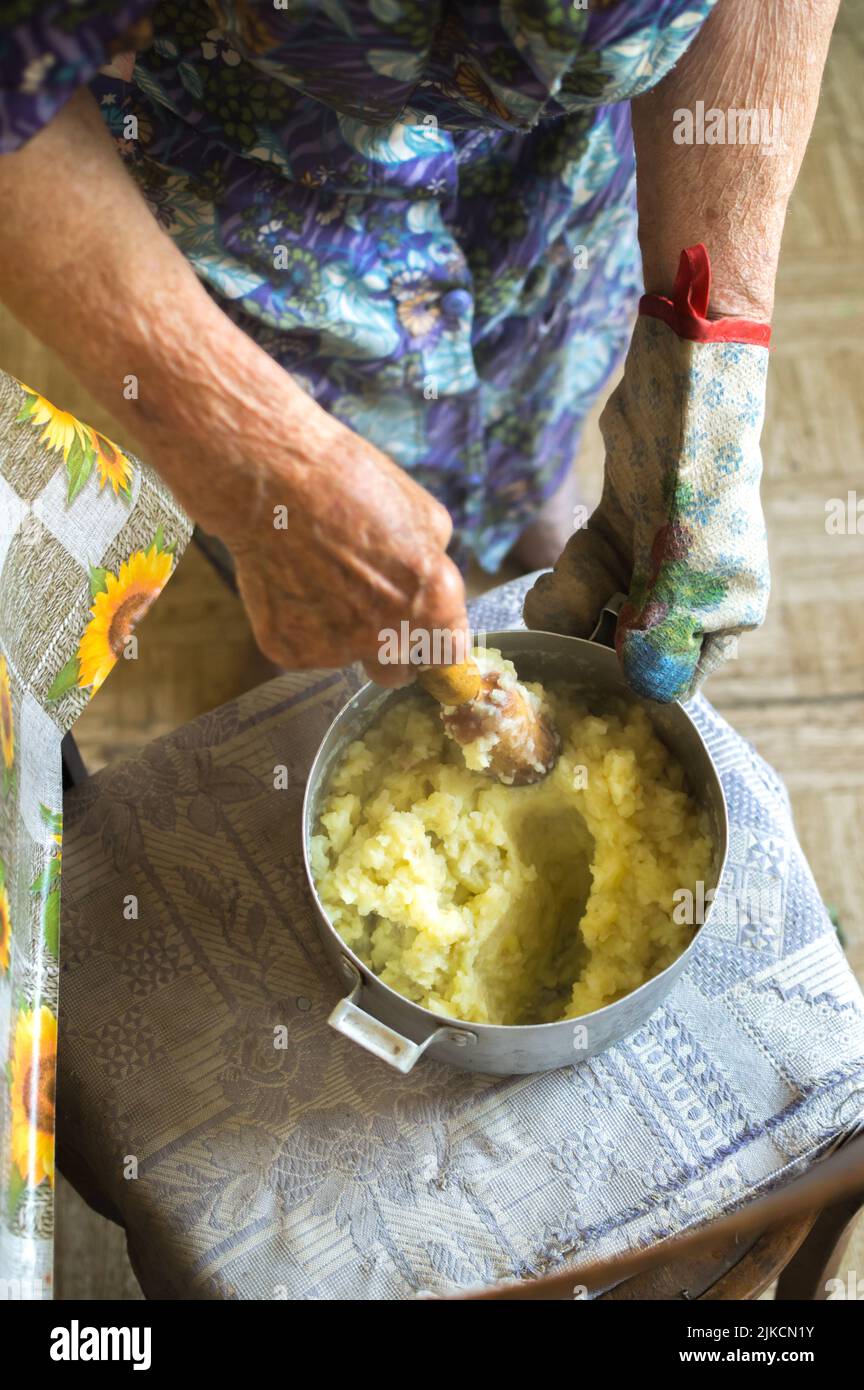 Old  grandmother cooking ground potatoes Stock Photo