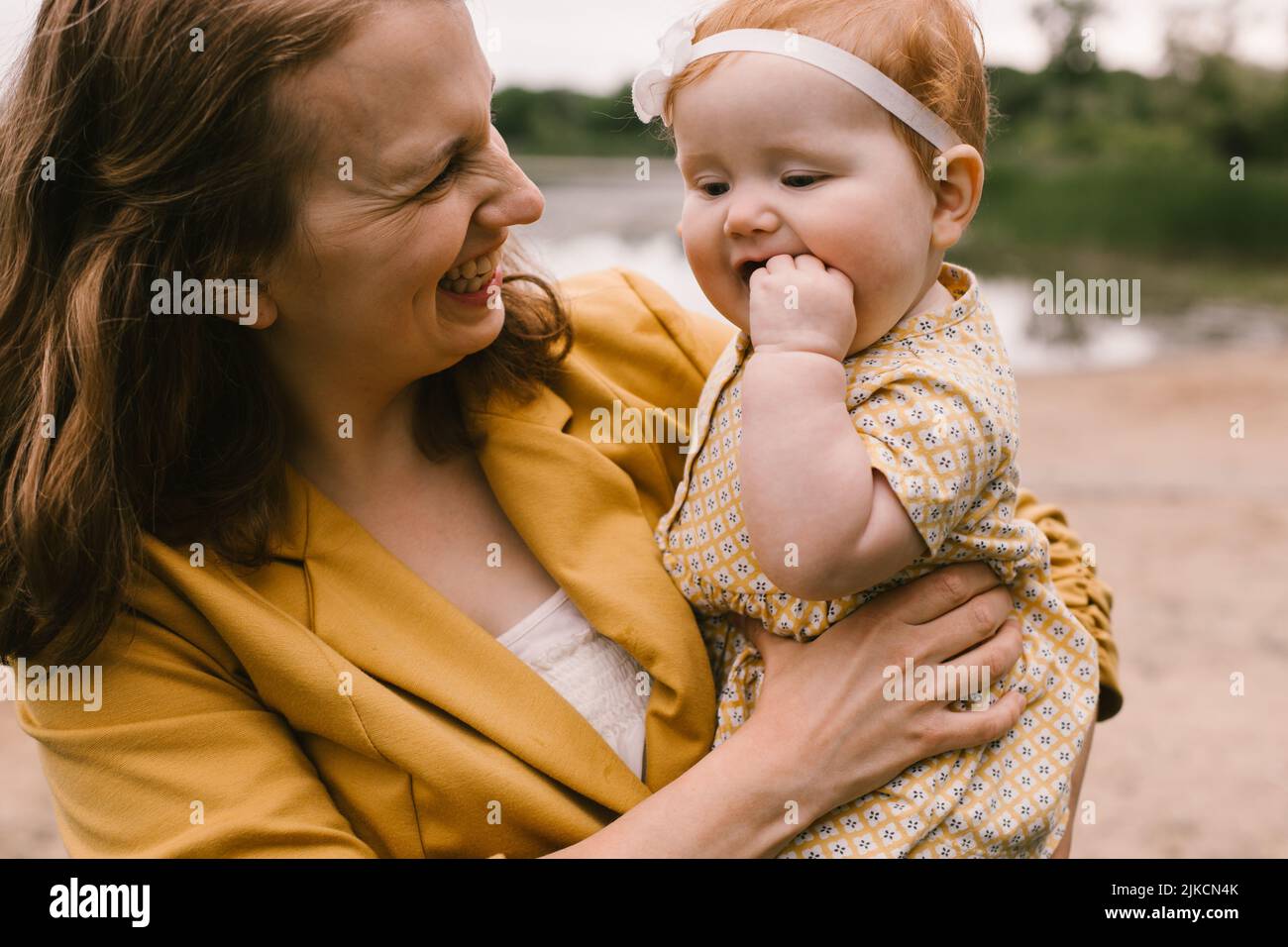 Mother laughs and smiles at red head baby daughter Stock Photo