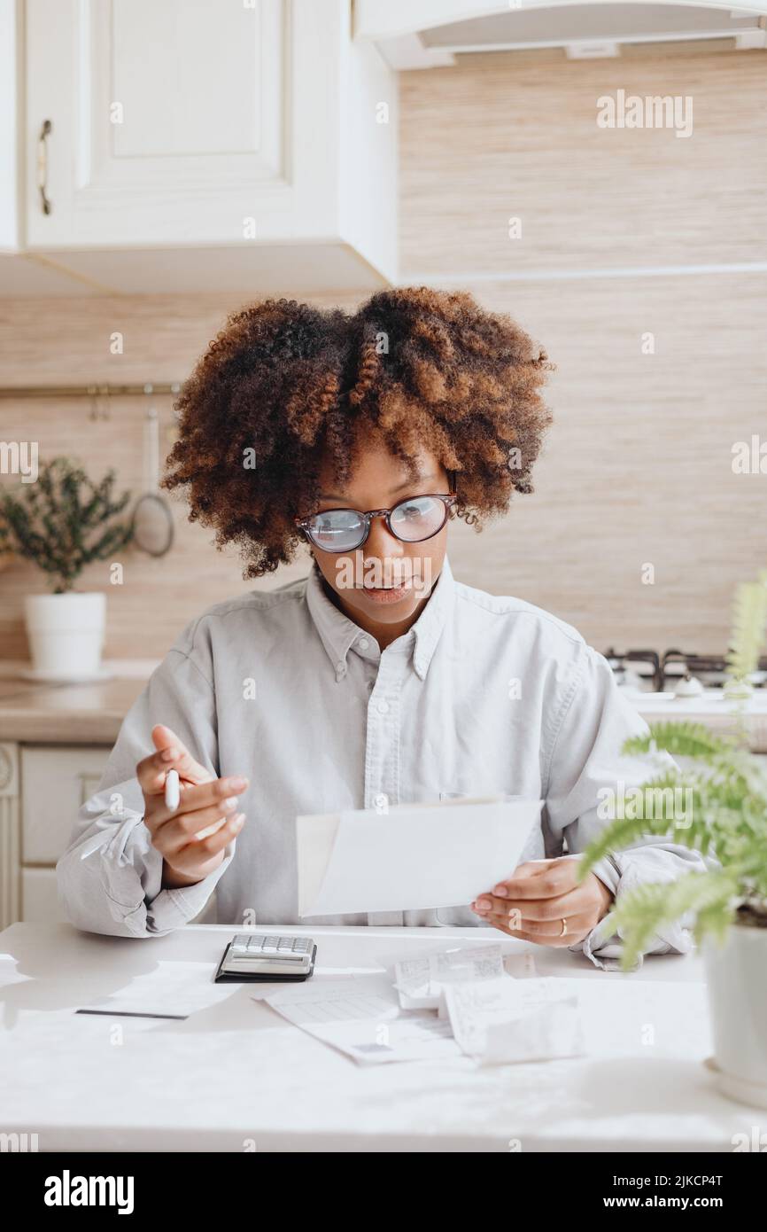 Curlyhaired woman pays bills at the kitchen table Stock Photo Alamy
