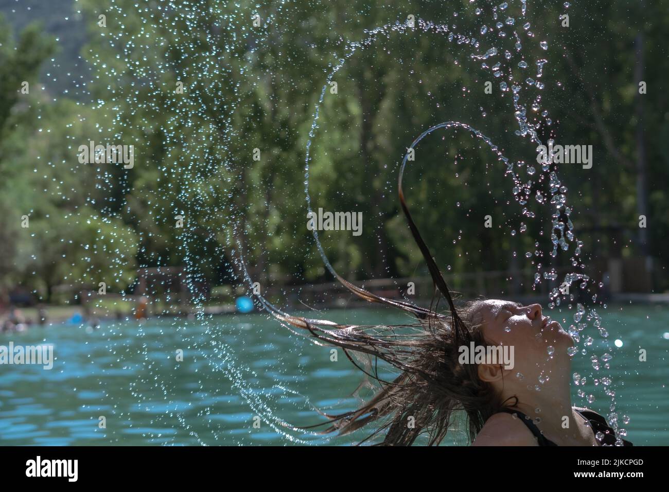long-haired brunette girl waving her hair in the water splash effect Stock Photo