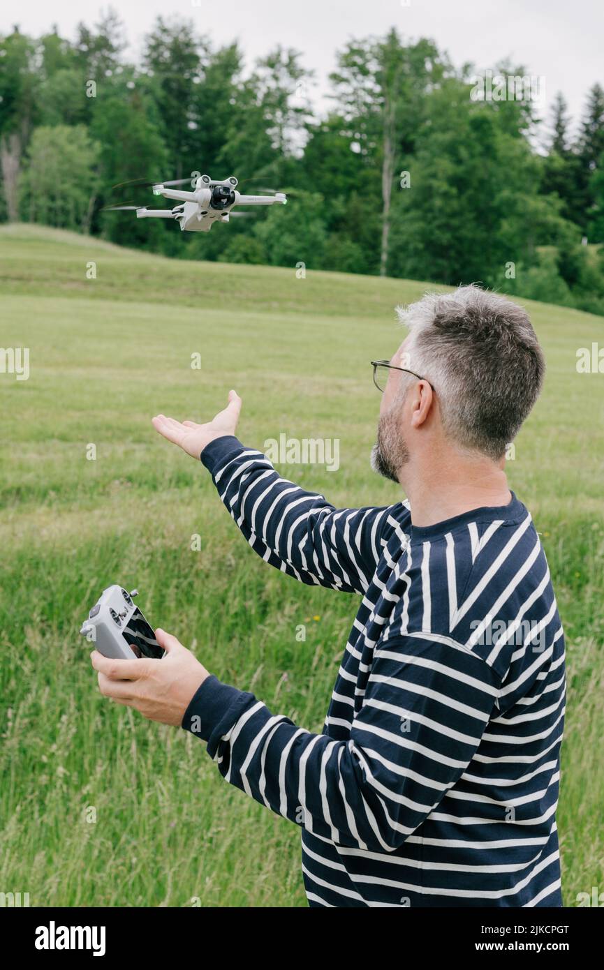 male hand catching drone quadcopter on meadow in Switzerland Stock Photo