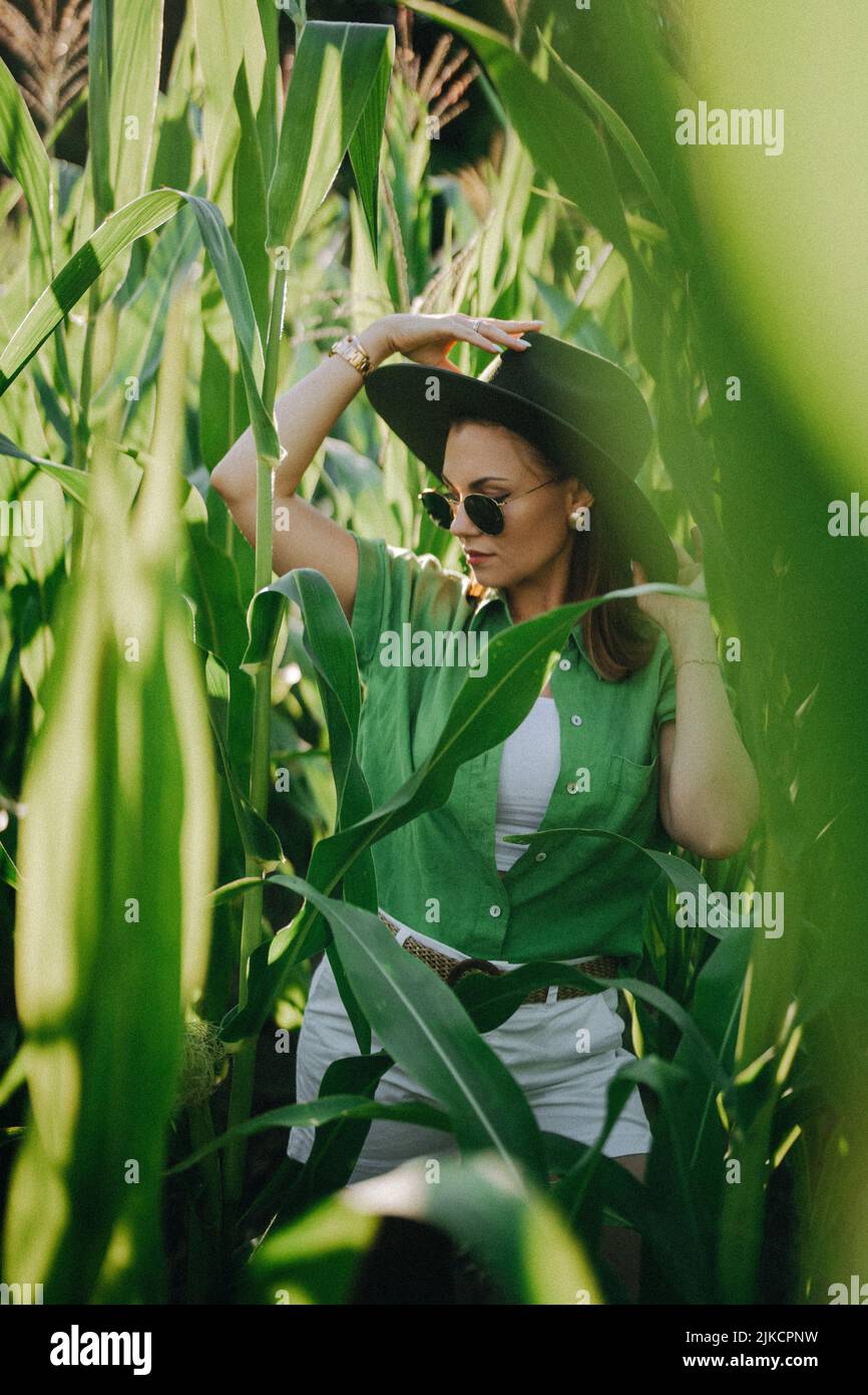 Portrait of stylish woman in jungle - corn plantation. Girl in hat Stock Photo