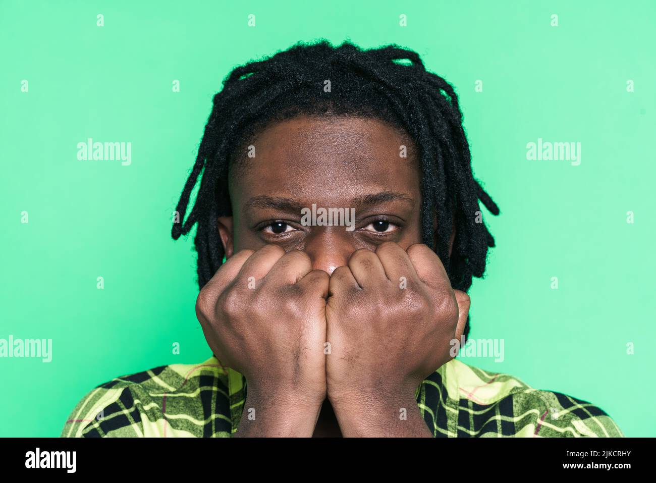 Young black man with dreadlocks posing with clenched fists isolated ...
