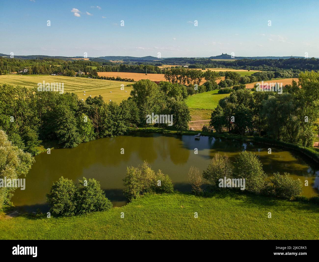 Pond, field, meadow and ruins of castle Trosky on horizon in Czech paradise in summer. Czech republic, village Lestkov pod Kozakovem. Aerial view from Stock Photo