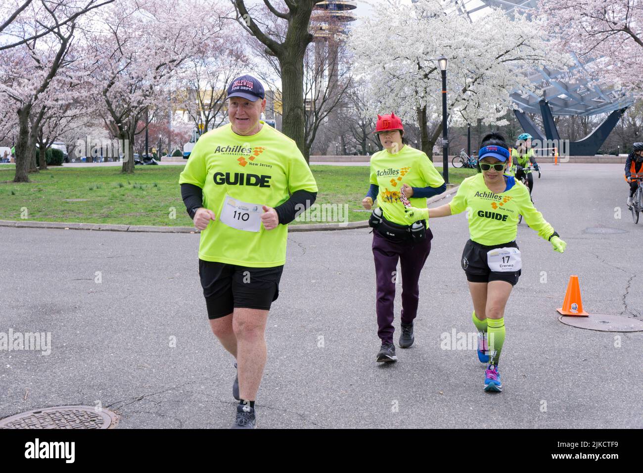 Volunteers from the New Jersey Achilles International track club guide an Asian American woman through a half marathon in a park in Queens, New York. Stock Photo