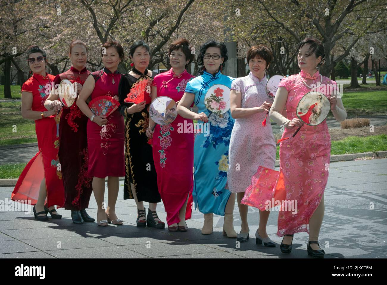 8 Chinese American members of a dance group pose for photos holding their fans. In Flushing Meadows Corona Park in Queens, New York City. Stock Photo
