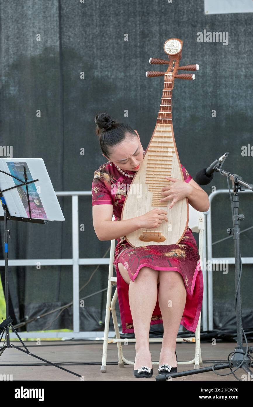 A  beautiful member of the Chinese Music Ensemble of New York plays the pipa, a traditional Chinese instrument. At the Hong Kong Dragon Boat Fest Stock Photo