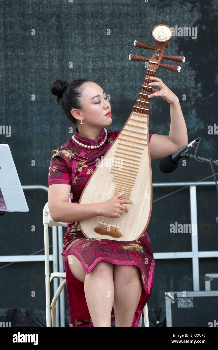 A  beautiful member of the Chinese Music Ensemble of New York plays the pipa, a traditional Chinese instrument. At the Hong Kong Dragon Boat Fest Stock Photo