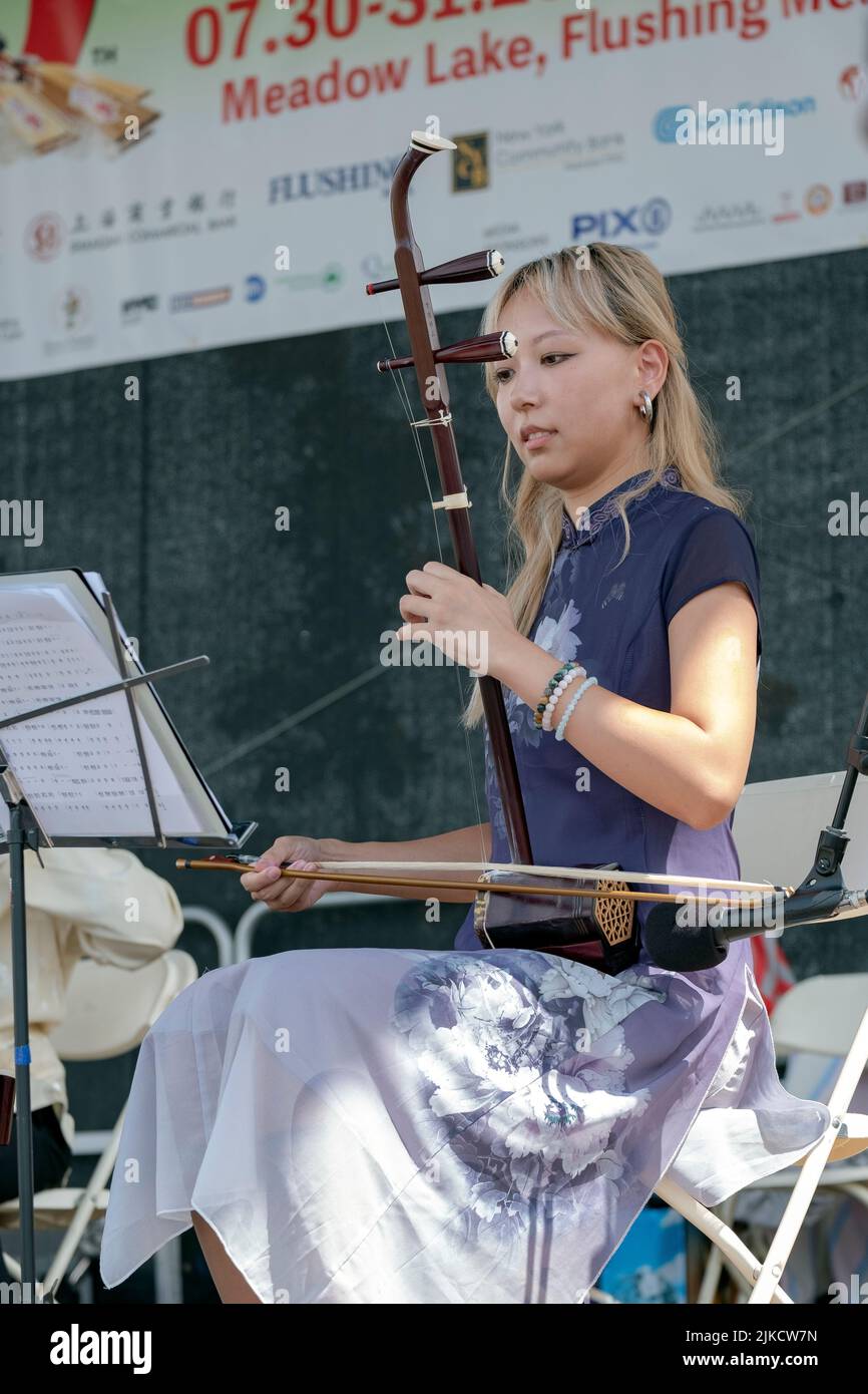 A  beautiful member of the Chinese Music ensemble of New York plays the erhu, a traditional Chinese instrument. At the Hong Kong Dragon Boat Fest, NYC Stock Photo