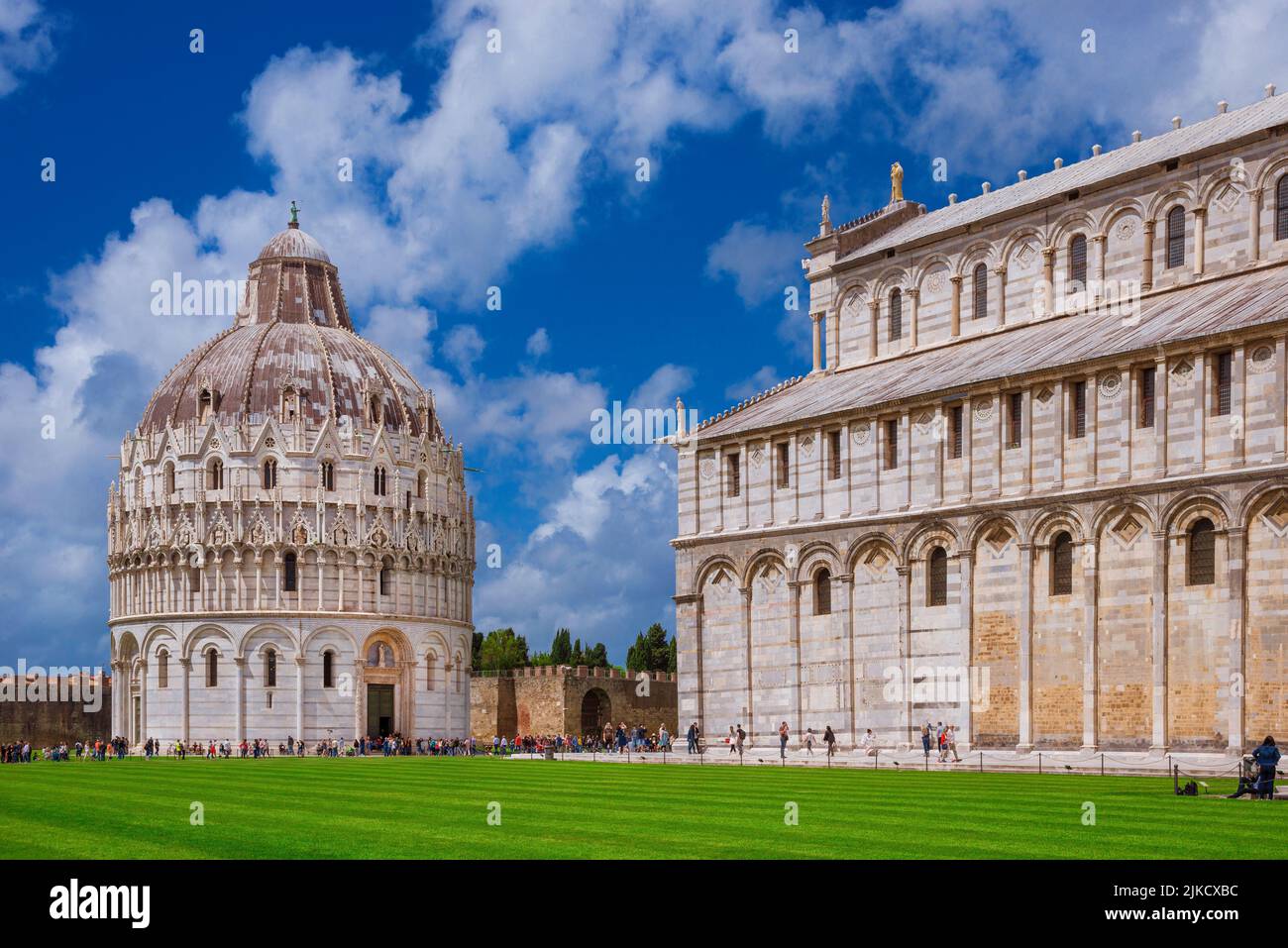 Sightseeing in Tuscany. Tourists visit the famous Campo dei Miracoli (Miracles' Square) with medieval Baptistery and Cathedral in Pisa Stock Photo