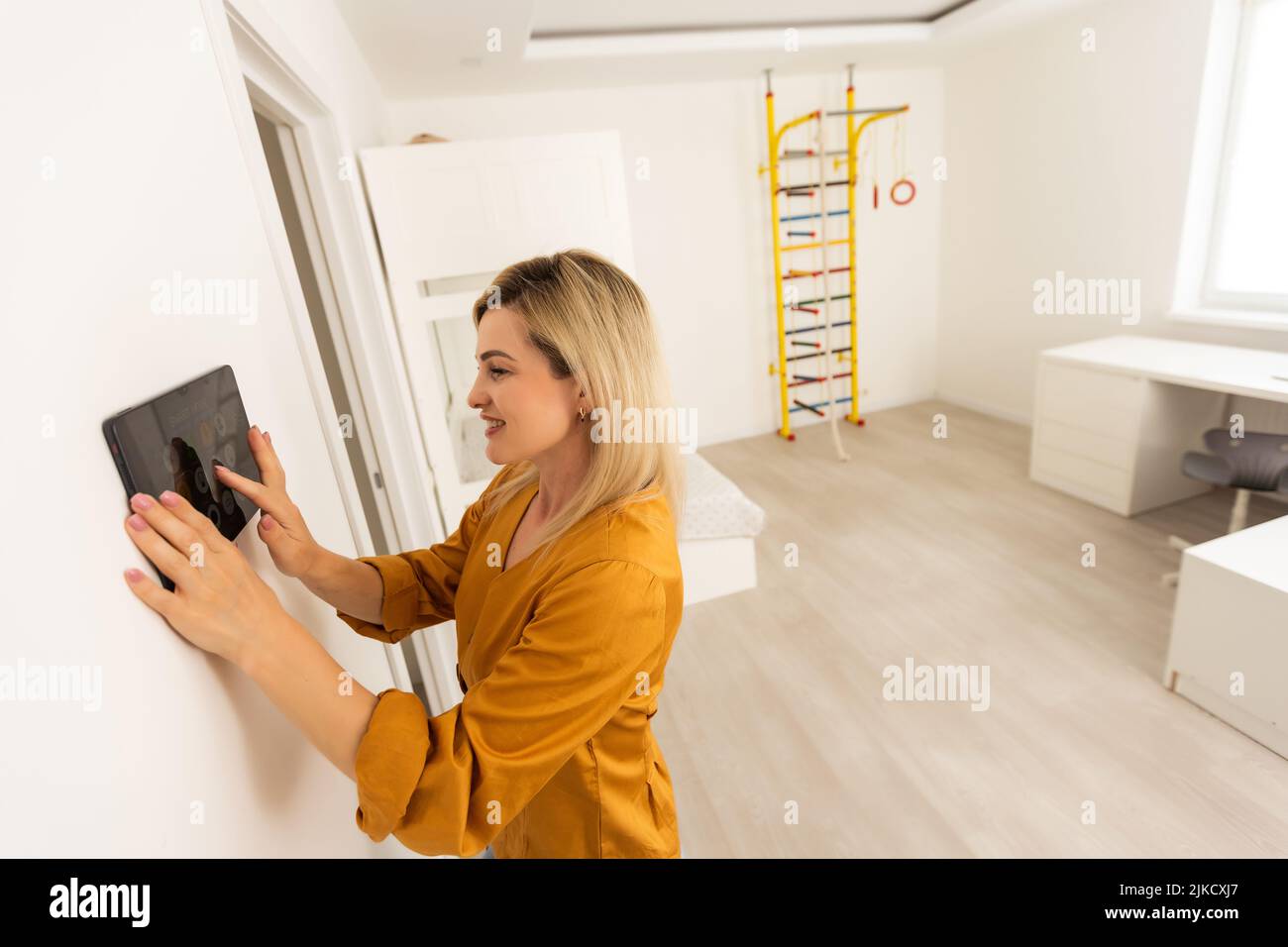 Woman using smart wall home control system. Stock Photo