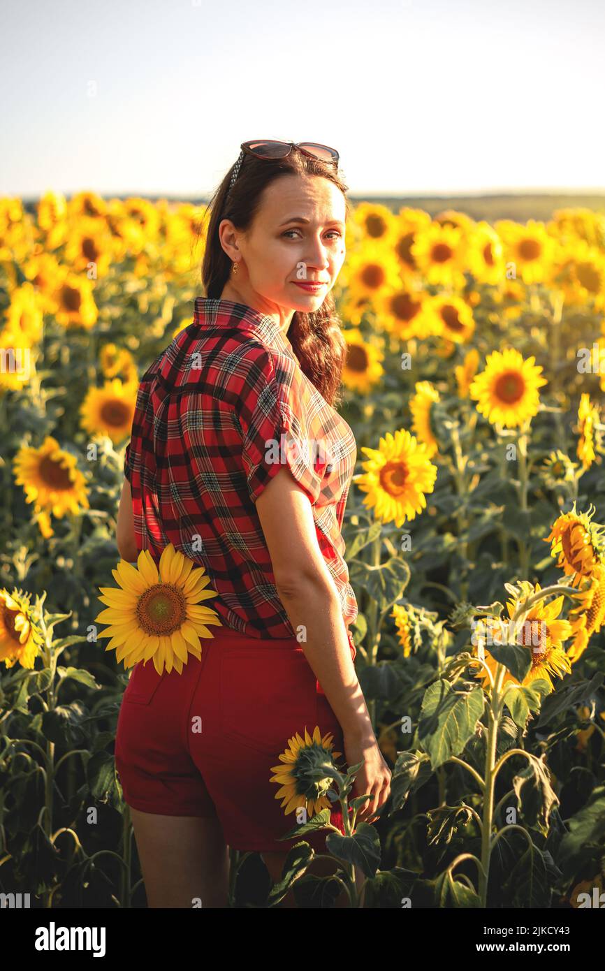 A young girl in a field of sunflowers at sunset. Portrait of a woman ...
