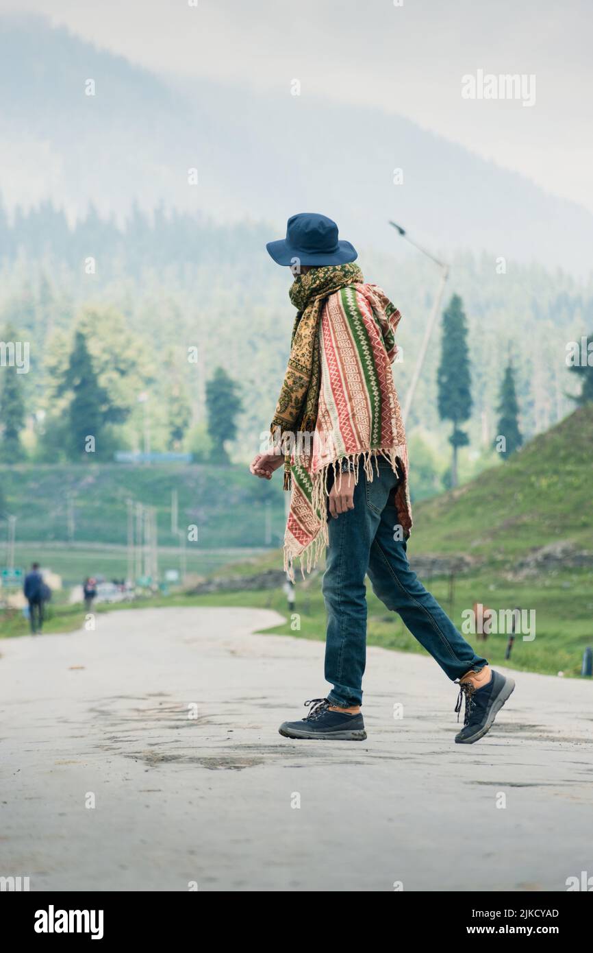Traveler walking into the horizon on the Ring Road of Gulmarg enjoying the scenery, Jammu and Kashmir, India. Stock Photo