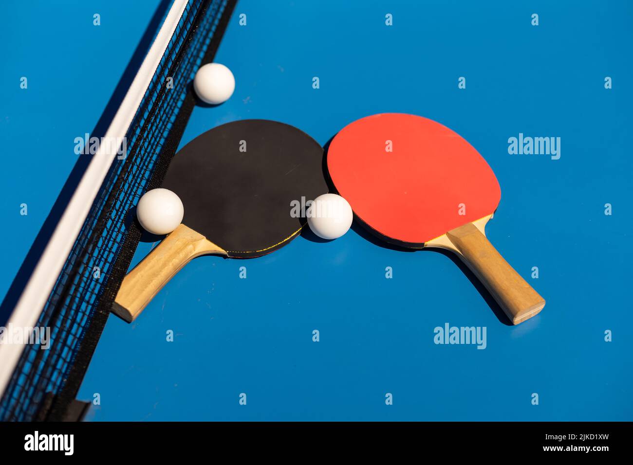 Table tennis rackets and a white plastic ball on a blue background