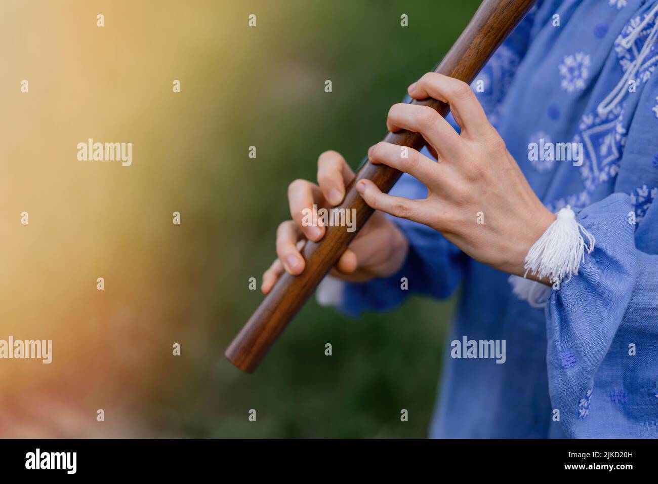 Woman playing woodwind wooden flute ukrainian sopilka outdoors. Folk