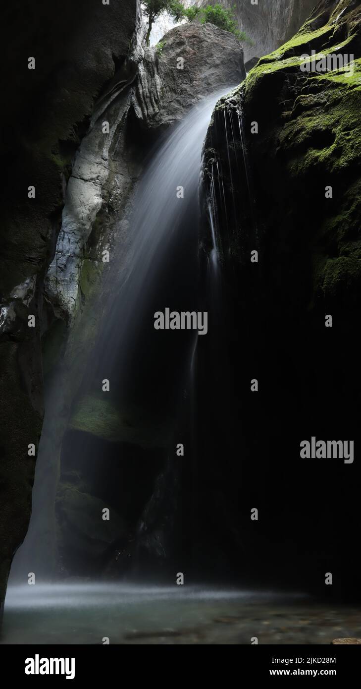 A vertical shot of the waterfall flowing over mossy rocks Stock Photo ...