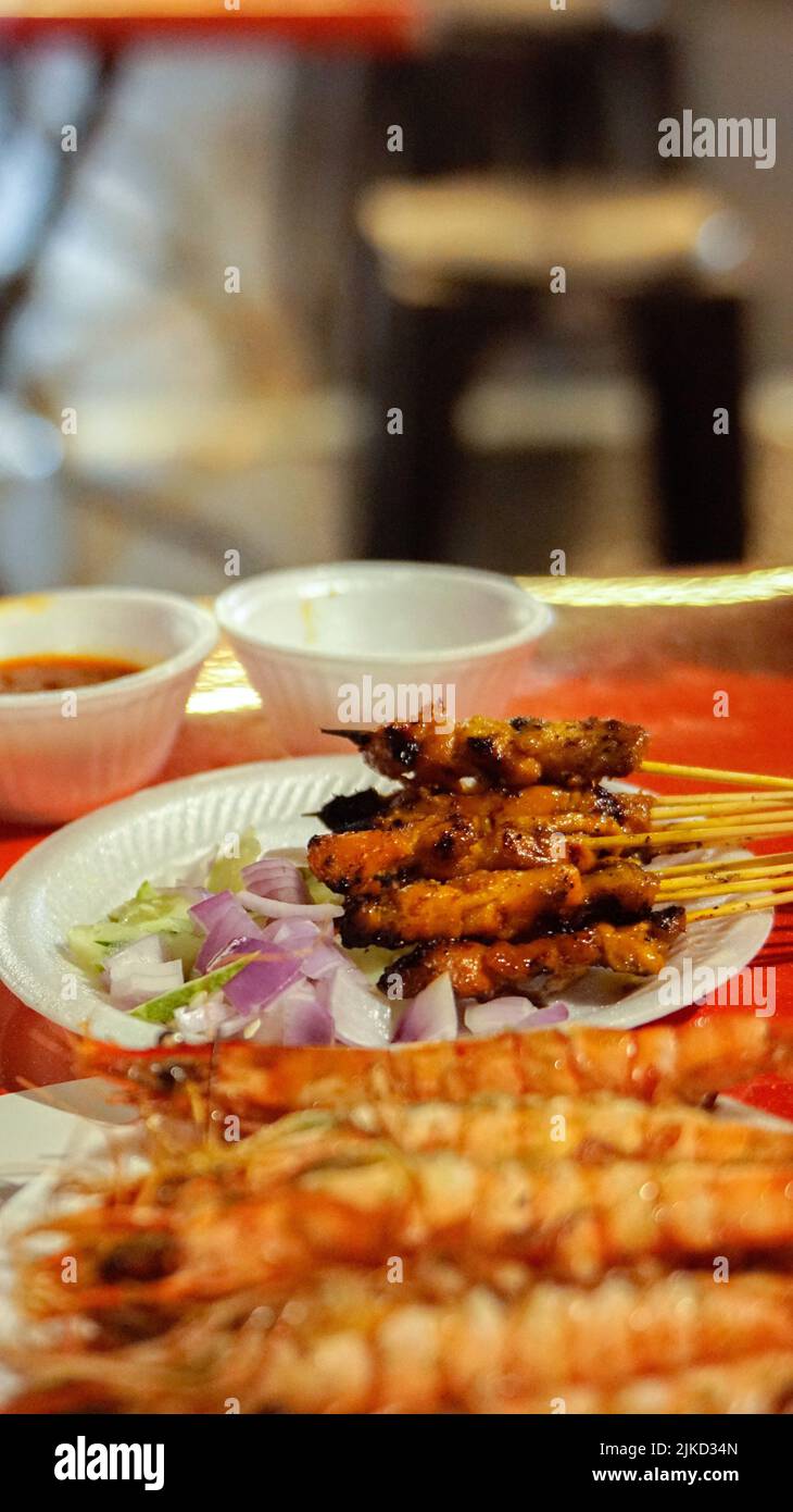 A vertical shot of Indonesian traditional satay dishes served with onions and sauces Stock Photo
