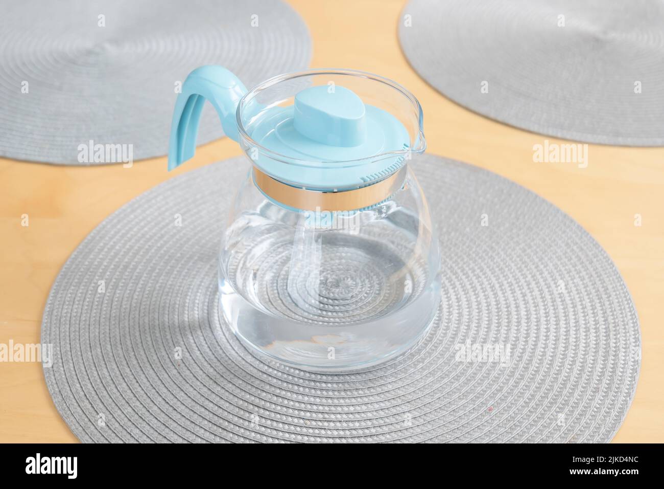 One modern light blue transparent jug full of clean fresh filtered drinking water laying on the table, object closeup, nobody, no people. Drinking wat Stock Photo