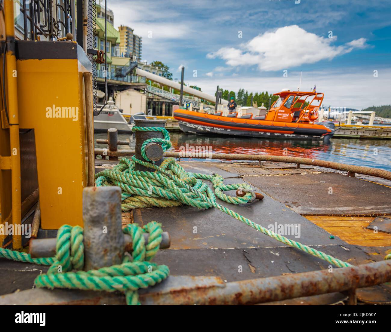 Mooring Bollard with rope on pier by the sea. Green Port rope. Mooring rope. Rope for fastening ships and cargo. Nobody Stock Photo
