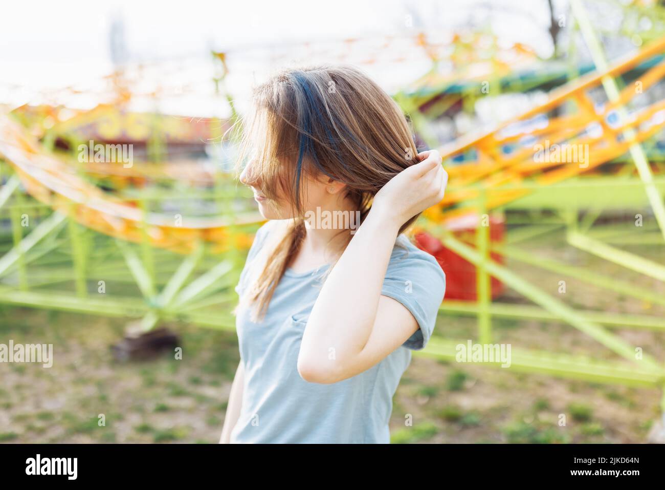 Happy young Gen Z woman with trendy blue hair in an amusement park