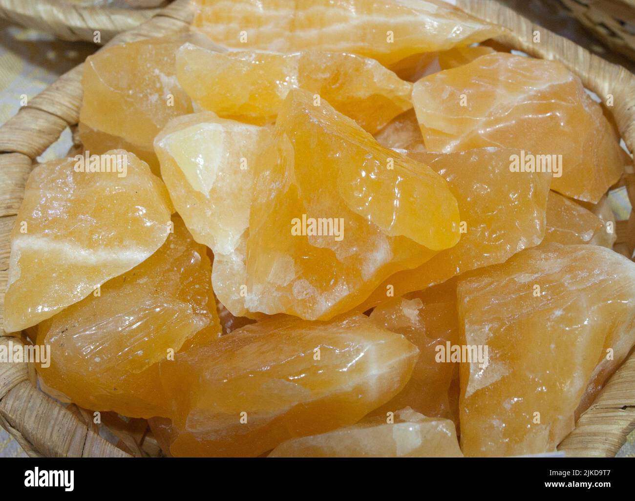 Yellow calcite fragments, believed to have beneficial health properties. Displayed on basket at street market stall. Stock Photo