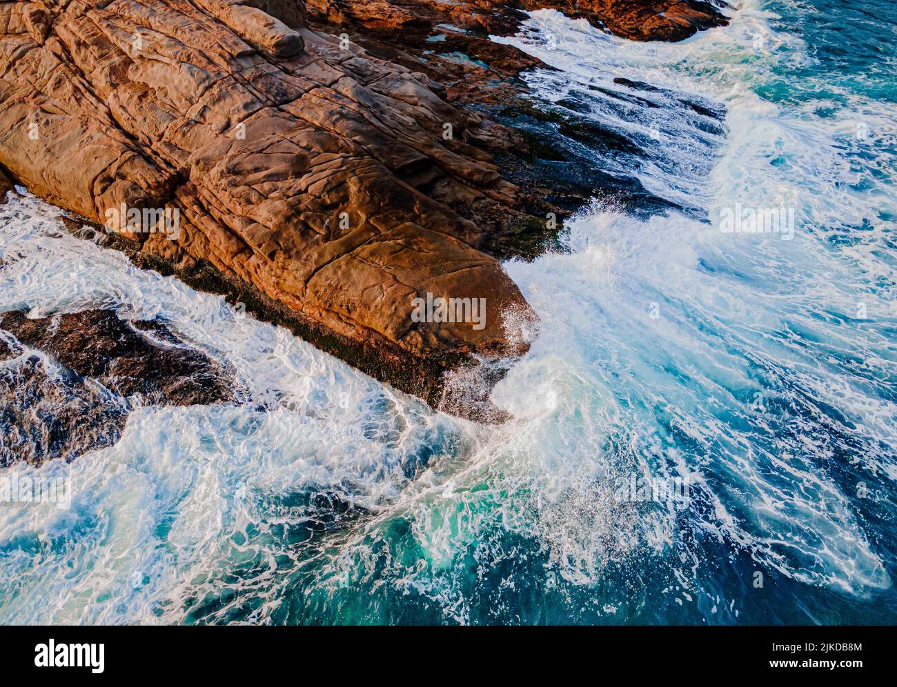 An aerial view of sea waves splashing against brown cliffs Stock Photo ...