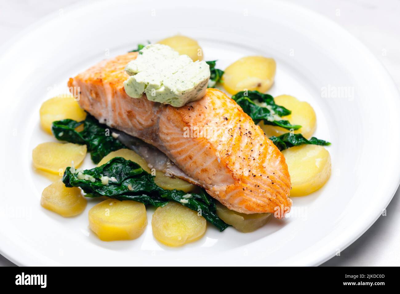baked salmon with spinach leaves and potatoes. Stock Photo