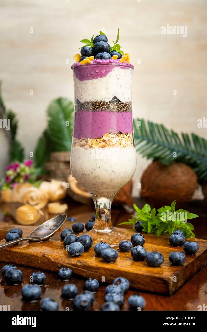 Blueberry smoothies with chia seeds in glass with fresh berries and mint on rustic wooden table. Stock Photo