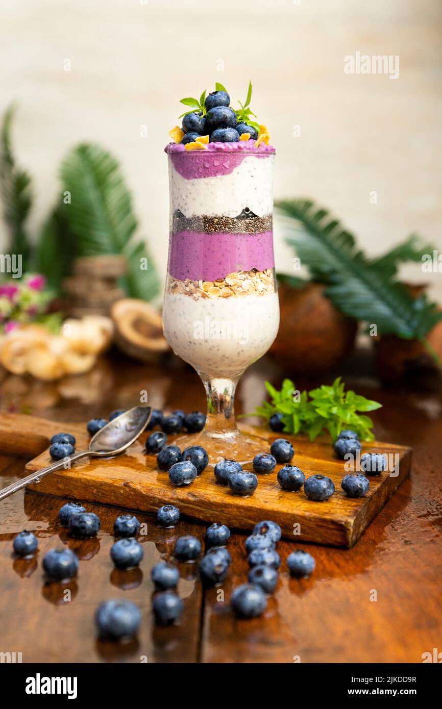 Blueberry smoothies with chia seeds in glass with fresh berries and mint on rustic wooden table. Stock Photo